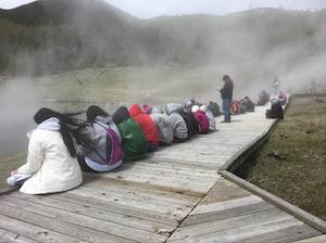 Students writing a reflection about their Making Civic Arguments projects while sitting on a boardwalk beside a geothermal feature at Yellowstone National Park. Photo Credit: Robin Hehn