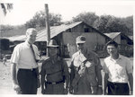 Sonny Montgomery poses with others in front of wooden complex