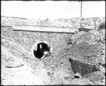 Man Inspecting Culvert by Mississippi Agriculture and Forestry Experiment Station. Delta Branch, Stoneville