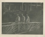 Three Airmen in Uniform, Seated on the Rail of a Bridge