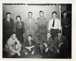 Nine Men and One Woman Posing in Front of a Blank Wall