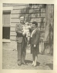 A Man, Woman, and Baby Posing in Front of a Building