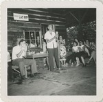 Man Performing on a Porch with Spectators