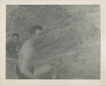 Two Men in Swim Trunks Sitting on a Sand Dune