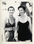 Two Women Standing on a Beach With Sand Dunes Behind Them