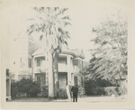 Two Uniformed United States Air Force Airmen Stand in Front of a Large House