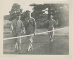 Airmen Walking Beside a Net on a Field With Trees Behind Them