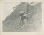Two Men in Swim Trunks Climbing a Sand Dune