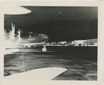 Negative Image of an Airplane on the Field with the Hangar Nearby