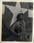 A Man in Coveralls and Cap Leaning Against a Plane