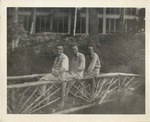 Three Airmen in Uniform, Seated on the Rail of a Bridge