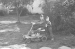 Two boys on lawn mower by Howard Langfitt