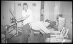 Student Getting Paddled by Friend in Dorm Room by Fred A. Blocker