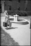 Student Walking by Fountain with Suitcases by Fred A. Blocker