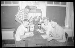 Students Sitting Around a Table Reading by Fred A. Blocker