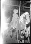 Child Riding Carousel by Fred A. Blocker