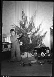 Boy Playing Next to Christmas Tree by Fred A. Blocker