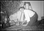 Man Playing Under Christmas Tree by Fred A. Blocker