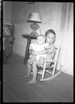 Boy Holding Baby in Rocking Chair by Fred A. Blocker