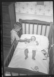 Boy Feeding Baby in Crib by Fred A. Blocker