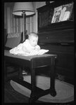 Baby Laying on Piano Bench by Fred A. Blocker